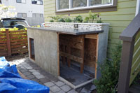 The shed under construction, showing the cement stucco exterior.  The shed includes space to manage electricity and water systems for the garden.