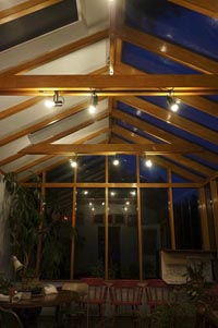 The exposed rafters and beams of the greenhouse lit at night.
