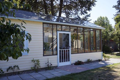 The left portion of the greenhouse is a storage room with floor-to-ceiling shelving.