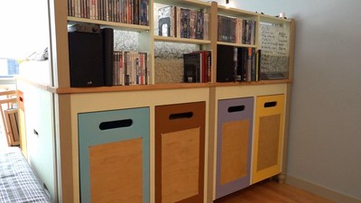 The bed frame includes a book case and facade that hides the bed behind it.